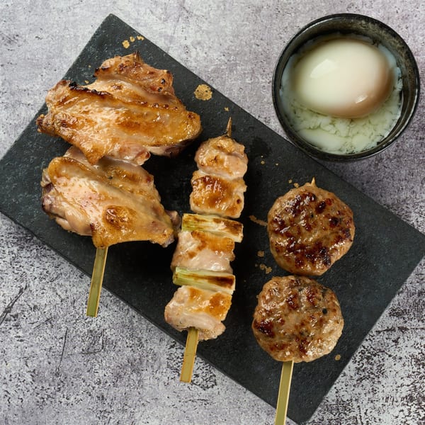 Assortment of grilled yakitori skewers, including chicken thighs, chicken and scallion, and chicken meatballs.